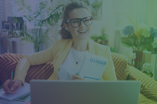 high school student with a textbook doing school work on a laptop