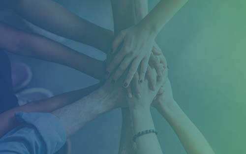 Teachers putting their hands in the middle.