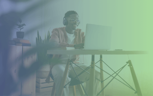 A student wearing headphones and glasses, sitting at a modern desk while using a laptop. The background features a potted plant and soft, natural lighting.